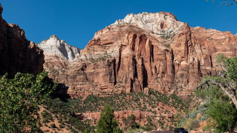 Red sandstone cliffs above a winding road and green trees